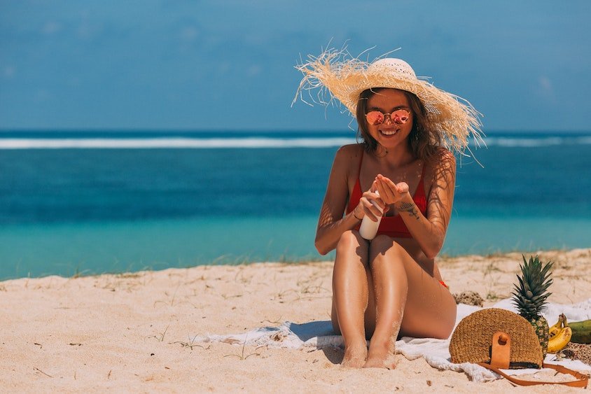 Sonnenbrand_Tipps-zur-Behandlung-und-Vorbeugung_Frau-cremt-sich-am-Strand-ein_2022